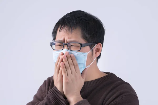 年轻的亚洲男人咳嗽着 感觉不舒服 呕吐着 戴着医疗用的蓝色面罩 隔离在白色的背景下 闭着眼睛 复制空间 — 图库照片