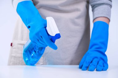 Genç bayan temizlikçi önlüklü beyaz masa temizliyor mavi eldivenli, sprey temizleyicili, ıslak sarı paçavralı, yakın plan, fotokopi alanı, boş tasarım konsepti..