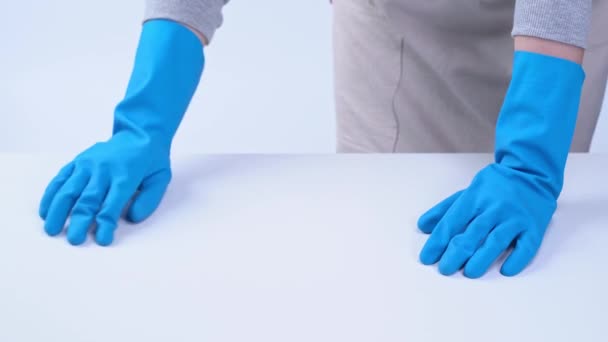 若い女性の家政婦は 青い手袋でエプロンで白いテーブルを掃除している スプレークリーナー 濡れた黄色のラグ 閉じます コピースペース 空白のデザインコンセプト — ストック動画