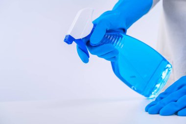 Genç bayan temizlikçi önlüklü beyaz masa temizliyor mavi eldivenli, sprey temizleyicili, ıslak sarı paçavralı, yakın plan, fotokopi alanı, boş tasarım konsepti..