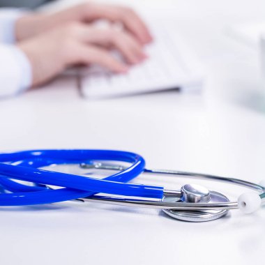 İş konsepti - ofiste bilgisayarla çalışan genç bayan doktor, elektronik tıbbi kayıt, beyaz masa arkaplanı, kapatın, boşluğu kopyalayın