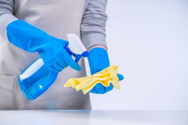 Genç bayan temizlikçi önlüklü beyaz masa temizliyor mavi eldivenli, sprey temizleyicili, ıslak sarı paçavralı, yakın plan, fotokopi alanı, boş tasarım konsepti..