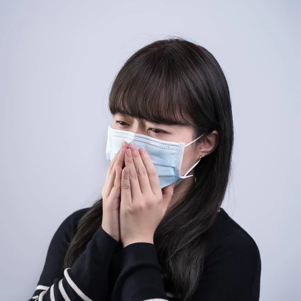 女性はマスクで咳をする 若いアジア人が口を覆い 白い背景に隔離された医療用の青い顔のマスクを身に着けていない感じ クローズアップ — ストック写真