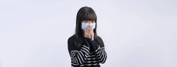 Woman coughing with face mask - young Asian covering the mouth by hand, feeling unwell illness isolated on white background, close up, copy space