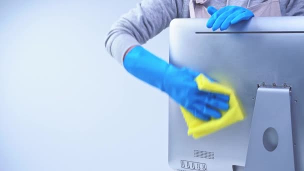 穿着围裙的年轻女管家正在打扫卫生 用蓝色手套擦拭办公室的电脑表面 湿透了的黄色抹布 4K特写 空白设计理念 — 图库视频影像