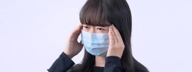 Genç kadın sersemlemiş, baş ağrısı, hasta, hasta, gri arka planda tıbbi mavi bir maske takıyor, yakın plan, kopyalama alanı.