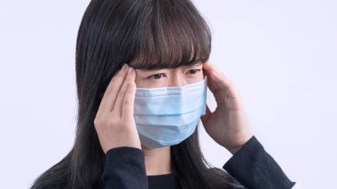 Genç kadın sersemlemiş, baş ağrısı, hasta, hasta, gri arka planda tıbbi mavi bir maske takıyor, yakın plan, kopyalama alanı.