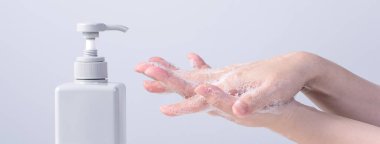 El yıkama. El yıkamak için sabun kullanan Asyalı genç kadın, gri beyaz arka planda izole edilmiş koronavirüsü yaymayı durdurmak için hijyen kavramı, yakın plan..