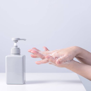 El yıkama. Asyalı genç kadın ellerini yıkamak için sıvı sabun kullanıyor, hijyen kavramı beyaz arka planda izole edilmiş koronavirüsü yaymayı durdurmak için, yakın plan.