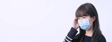 Genç kadın sersemlemiş, baş ağrısı, hasta, hasta, gri arka planda tıbbi mavi bir maske takıyor, yakın plan, kopyalama alanı.