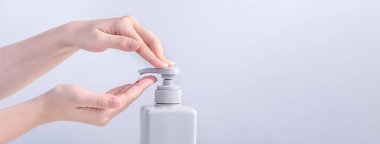 El yıkama. Asyalı genç bir kadın ellerini yıkamak için sıvı sabun kullanıyor, koruyucu pandemik koronavirüs konsepti gri beyaz arka planda izole edilmiş, kapatın..