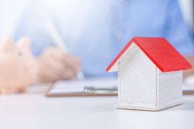 İş konsepti - Mavi gömlekli genç Asyalı adam ev kredisi ödemesi, ödeme sigortası, vergi ödeme anlaşmasını hesaplar, imzalar, kapatır.