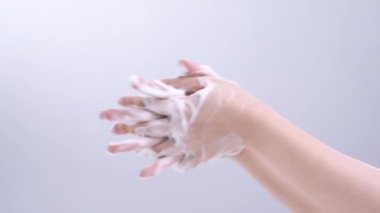El yıkama talimatları. Asyalı genç bir kadın ellerini yıkamak için sıvı sabun kullanıyor. Beyaz arka planda izole edilmiş koronavirüs yaymayı durdurmak için hijyen kavramı..