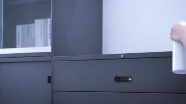 Genç kadın elinde sprey şişesi, temizlenecek bez parçası, ofis metali raf konaklama yüzeyi, kapanış, yaşam tarzı, antibakteriyel konsept.