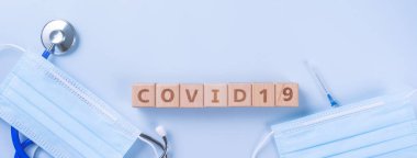 COVID-19 kelime ahşap küp maske, tıbbi ekipman, dünya hastalığı salgını enfeksiyonu ve önleme konsepti, üst görünüm, düz konum, genel tasarım
