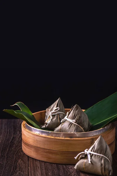 Zongzi - Çin pirinçli zongzi hamur tatlısı ahşap masa üzerinde siyah arka plan Ejderha Teknesi Festivali kutlamaları için, kapatın, kopyalayın.