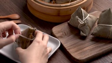 Zongzi yiyor - Genç kız evinde Çin pirinçli börek yiyor, Ejderha Teknesi Festivali için, Duanwu Festivali için, siyah ahşap masada..