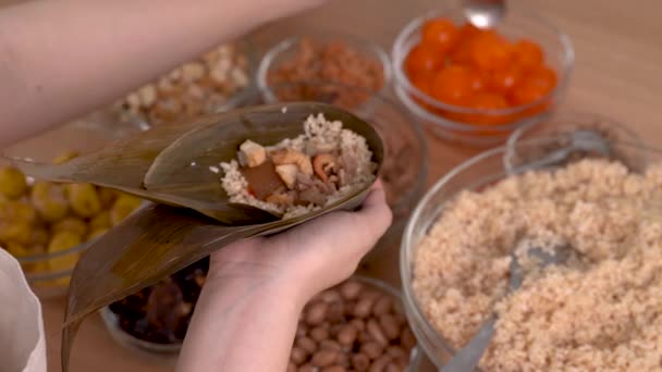 宗子を作る 家族はドラゴンボートフェスティバルのお祝いのために自宅で木製のテーブルの上で一緒に作る中国の米団子宗子の食品成分を準備し クローズアップ ライフスタイル — ストック動画