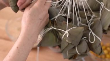Zongzi hazırlamak, aile hazırlamak, Çin pirinçlerini paketlemek, zongzi yemeklerini evde ahşap masaya koymak Ejderha Teknesi Festivali için, kapanış, yaşam tarzı.