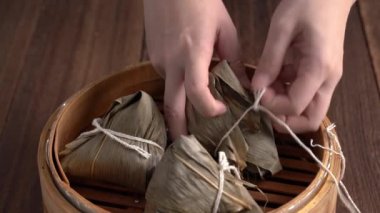 Zongzi yiyor - Genç kız evinde Çin pirinçli börek yiyor, Ejderha Teknesi Festivali için, Duanwu Festivali için, siyah ahşap masada..