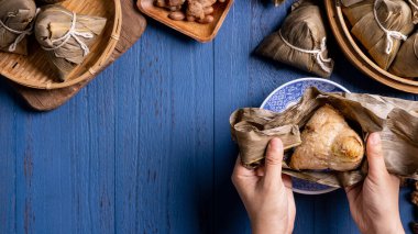 Pirinç köftesi, zongzi - Ejderha Teknesi Festivali 'nin mavi ahşap arka planında geleneksel Çin yemeği, Duanwu Festivali, üst manzara, düz dizayn konsepti.