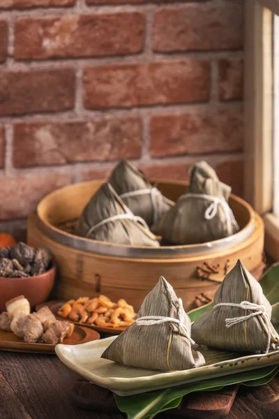 Rice dumpling, zongzi - Chinese rice dumpling zongzi in a steamer on wooden table with red brick, window background at home for Dragon Boat Festival concept, close up.