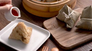 Pirinç hamurlu zongzi yemek - Genç kız evde Çin yemeği yiyor, Ejderha Teknesi Festivali için, Duanwu Festivali için, siyah ahşap masada..
