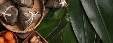Pirinç köftesi, zongzi - Ejderha Teknesi Festivali 'nin yeşil yapraklı arka planında geleneksel Çin yemeği, Duanwu Festivali, üst manzara, düz dizayn konsepti.
