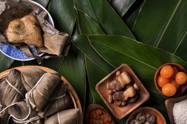 Pirinç köftesi, zongzi - Ejderha Teknesi Festivali 'nin yeşil yapraklı arka planında geleneksel Çin yemeği, Duanwu Festivali, üst manzara, düz dizayn konsepti.