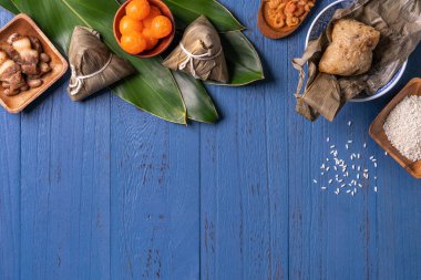 Ejderha Botu Festivali konsepti - Pirinç köftesi, zongzi, Duanwu Festivali için mavi ahşap arka planda geleneksel Çin yemeği, üst manzara, düz dizayn konsepti.