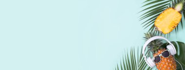 Beyaz kulaklık takan komik ananas, müzik dinleme konsepti, tropik palmiye yaprakları ile izole edilmiş renkli arka plan, üst görünüm, düz dizayn.