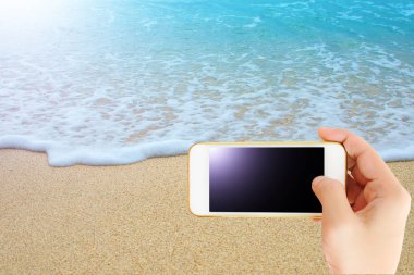 Elini tut güzel mavi deniz ve kum, seyahat konsepti ile akıllı telefon. tuch ekran kırpma yolu ile.