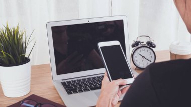 Kadın el smartphone ve dizüstü bilgisayar arka plan kullanarak işyeri tablodur