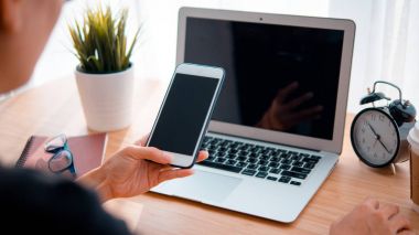 Kadın el smartphone ve dizüstü bilgisayar arka plan kullanarak işyeri tablodur