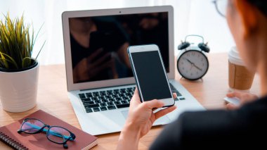 Kadın el smartphone ve dizüstü bilgisayar arka plan kullanarak işyeri tablodur