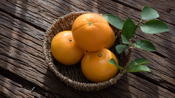 Basket of orange fruit set on wood table.