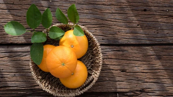 Basket of orange fruit set on wood table.