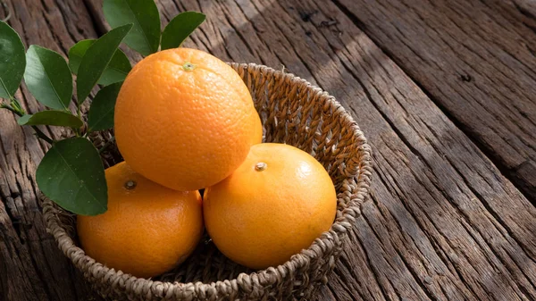 Basket of orange fruit set on wood table.