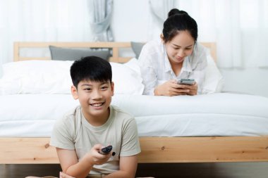 Asyalı kadın yatakta televizyon izlerken Asya çocukla.