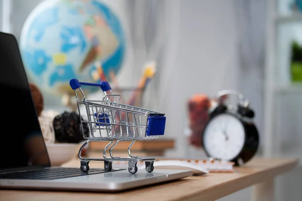 Mini shopping cart on computer laptop. Business concept.