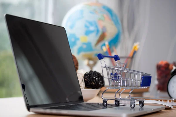 Mini shopping cart on computer laptop. Business concept.