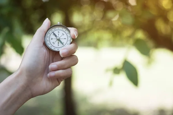 Kompassen i handen med bakgrund av grön natur. — Stockfoto