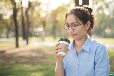 Asyalı kadın yeşil mutlu duygu ile sıcak kahve içme 