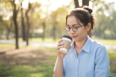 Asyalı kadın yeşil mutlu duygu ile sıcak kahve içme 