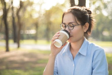 Asyalı kadın yeşil mutlu duygu ile sıcak kahve içme 