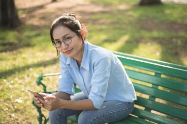 Asyalı kadın gargen bankta oturmuş.