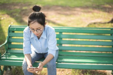 Asyalı kadın gargen bankta oturmuş.