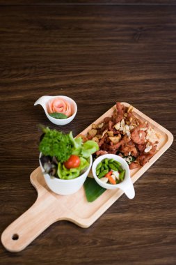 Sarımsaklı kızarmış domuz. Derin kızarmış gevrek domuz eti pişmiş sarımsak ve ahşap masa arka plan üzerinde baharatlı daldırma sos ile