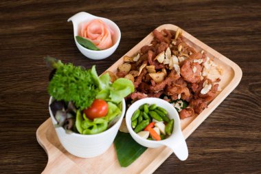 Sarımsaklı kızarmış domuz. Derin kızarmış gevrek domuz eti pişmiş sarımsak ve ahşap masa arka plan üzerinde baharatlı daldırma sos ile