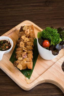 Sarımsaklı kızarmış domuz. Derin kızarmış gevrek domuz eti pişmiş sarımsak ve ahşap masa arka plan üzerinde baharatlı daldırma sos ile